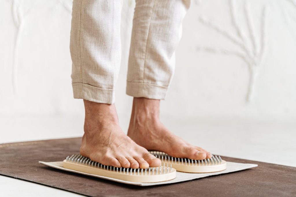 Close-up of an adults feet practicing acupressure with a Sadhu board indoors.